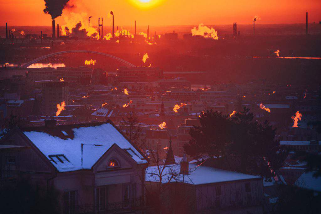 Winter morning in the city. Orange smoke from chimney. Industrial Factory and smoke in background. Ecology, pollution concept photo. Bratislava, Slovakia, 