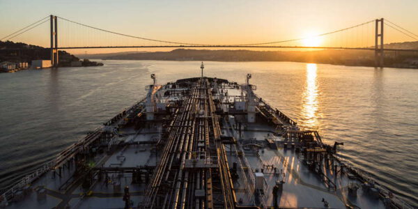 Oil tanker is passing through Bousphorus strait when it sunset.