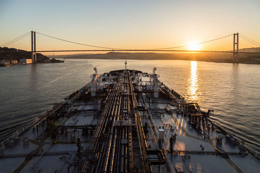 Oil tanker is passing through Bousphorus strait when it sunset.